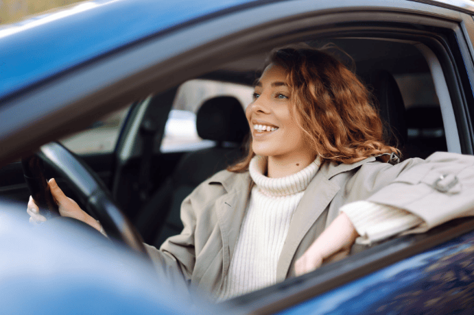 Conductrice souriante au volant illustrant l’autopartage et la mobilité durable en entreprise.
