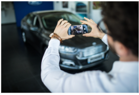 Homme prenant en photo un véhicule avec son smartphone, illustrant la digitalisation du secteur automobile et ses usages dans la gestion de flotte.