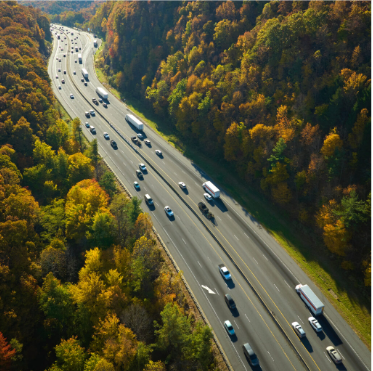 Vue aérienne d’une autoroute traversant une zone boisée, illustrant le partenariat entre SONATEL et Océan pour accompagner la transition écologique et numérique des transports au Sénégal.
