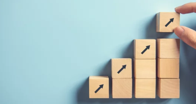 progression-croissance-blocs-fleche.png Blocs de bois empilés en escalier avec des flèches indiquant une progression et une croissance vers le haut.