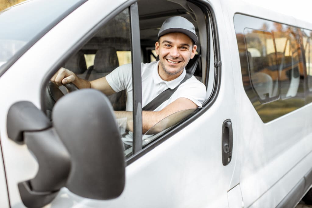 Conducteur souriant au volant d’un véhicule utilitaire illustrant la gestion de flotte professionnelle.