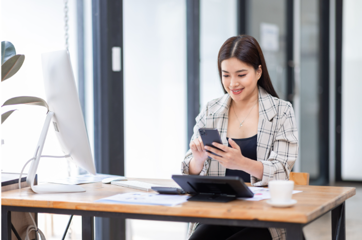 Salariée utilisant son smartphone au bureau, illustrant la gestion de flotte et la transition vers la mobilité électrique.
