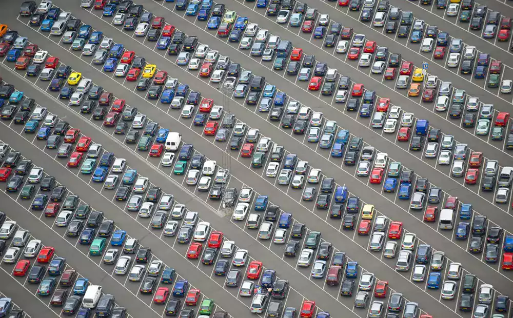 Vue aérienne d’un grand parking rempli de véhicules, illustrant la gestion d’une flotte automobile d’entreprise.