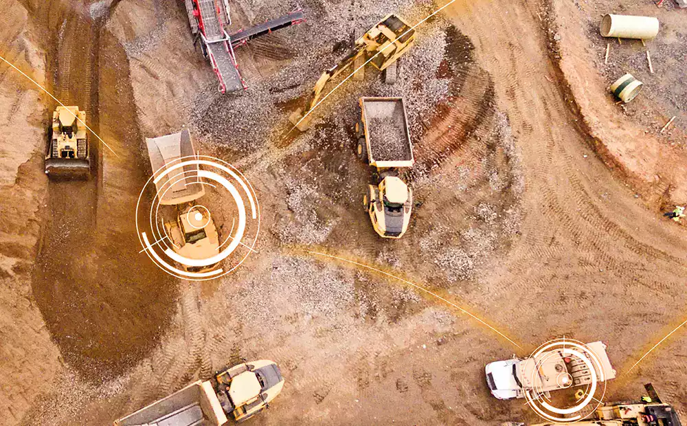 Vue aérienne d’un chantier BTP avec des engins connectés et géolocalisés pour le suivi des opérations.