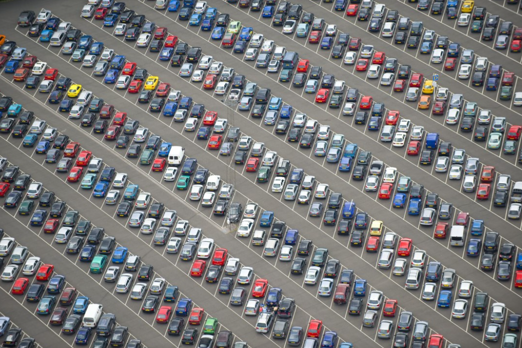Vue aérienne d’un grand parking rempli de véhicules, illustrant l’optimisation de la gestion de flotte automobile avec la solution Océan.