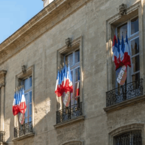 obligations-collectivites-flottes-vehicules-faibles-emissions.webp Façade d’un bâtiment officiel français décoré de drapeaux tricolores, symbolisant les obligations légales des collectivités en matière de transition vers des véhicules à faibles émissions.