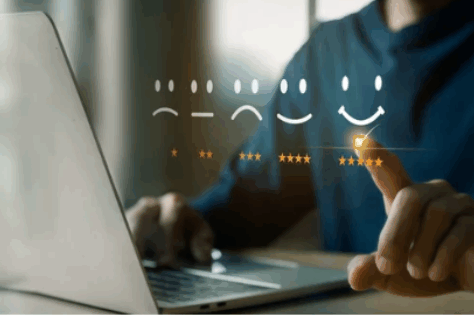 Main sélectionnant une évaluation positive à cinq étoiles sur un ordinateur, symbolisant la satisfaction client et l’usage d’outils numériques.