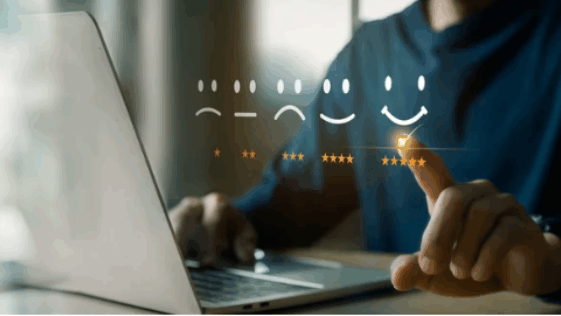 Main sélectionnant une évaluation positive à cinq étoiles sur un ordinateur, symbolisant la satisfaction client et l’usage d’outils numériques.