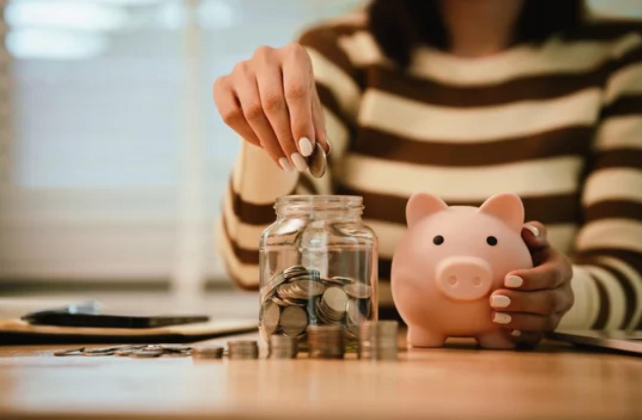 economies-gestion-flotte-entreprise.png Personne déposant des pièces dans un bocal près d’une tirelire, symbolisant les économies réalisées grâce à l’optimisation de la gestion de flotte.