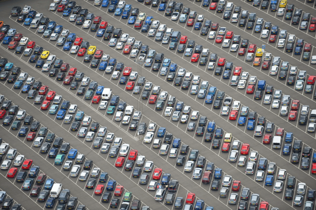Vue aérienne d’un grand parking rempli de véhicules, illustrant l’optimisation de la gestion de flotte automobile avec la solution Océan.